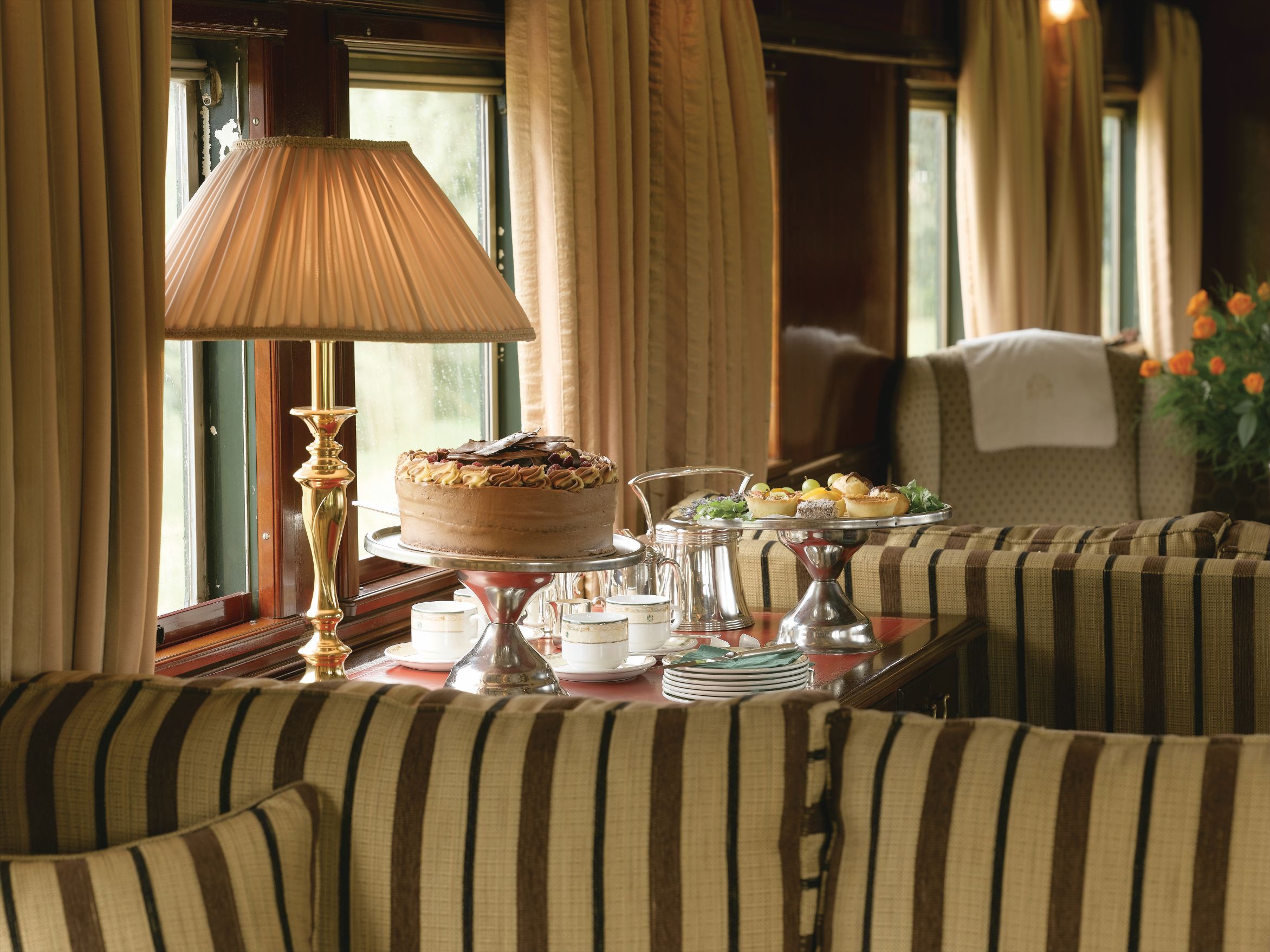 Eleganter Afternoon Tea mit Kuchen und Gebäck im luxuriösen Salonwagen des Rovos Rail Zuges in Südafrika.