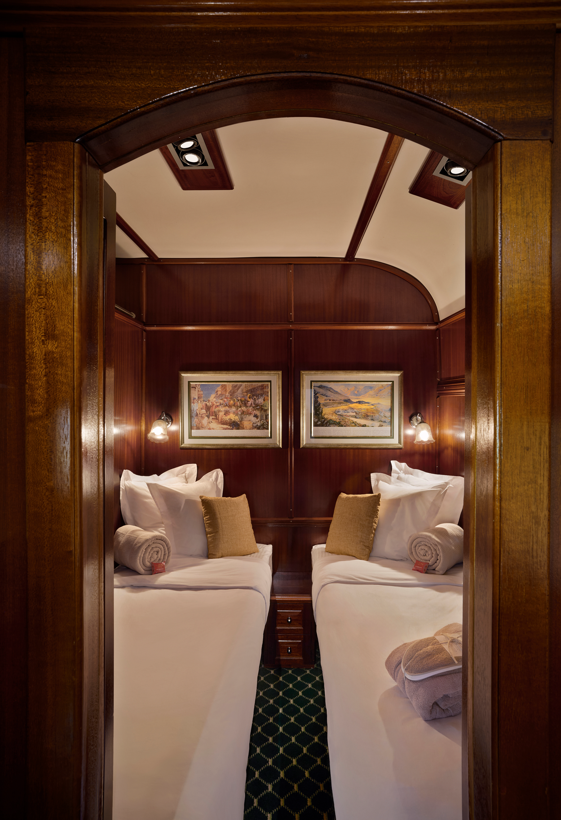 Elegante Deluxe-Suite im Rovos Rail Luxuszug mit Holzvertäfelung, zwei Einzelbetten und klassischem Ambiente während einer Reise durch Südafrika.