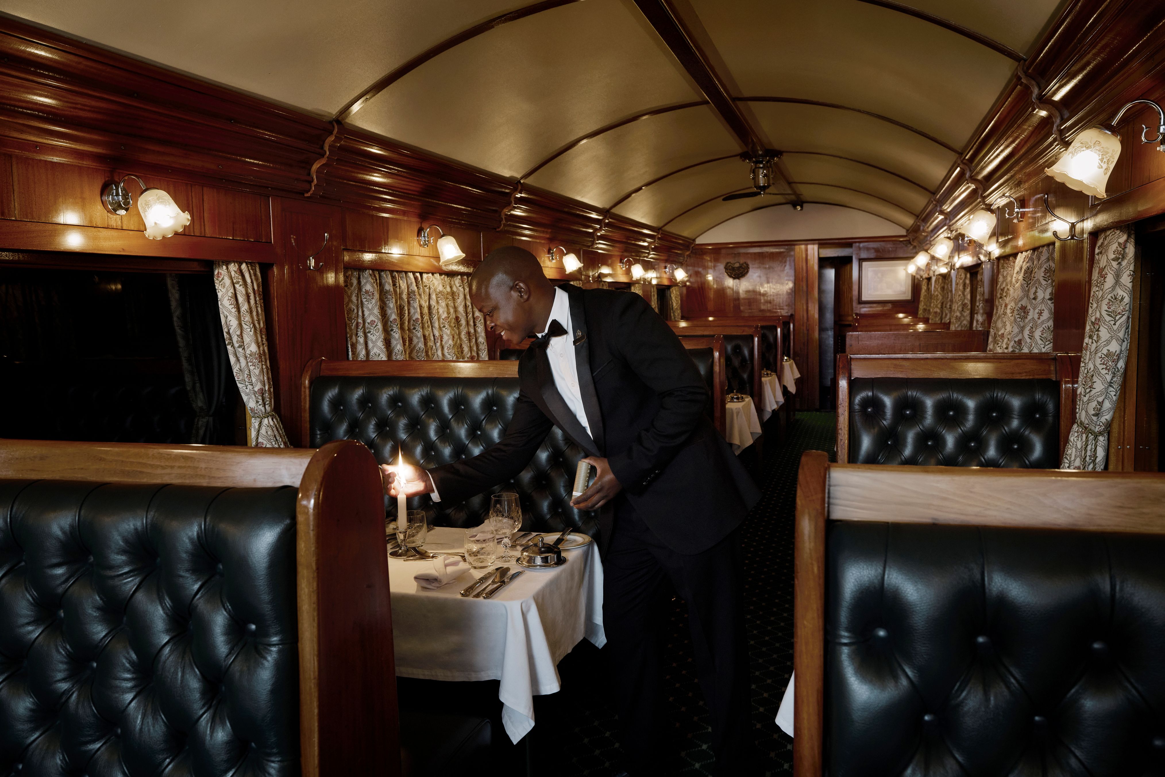 Service im luxuriösen Speisewagen des Rovos Rail mit stilvoll gedeckten Tischen und klassischem Ambiente.