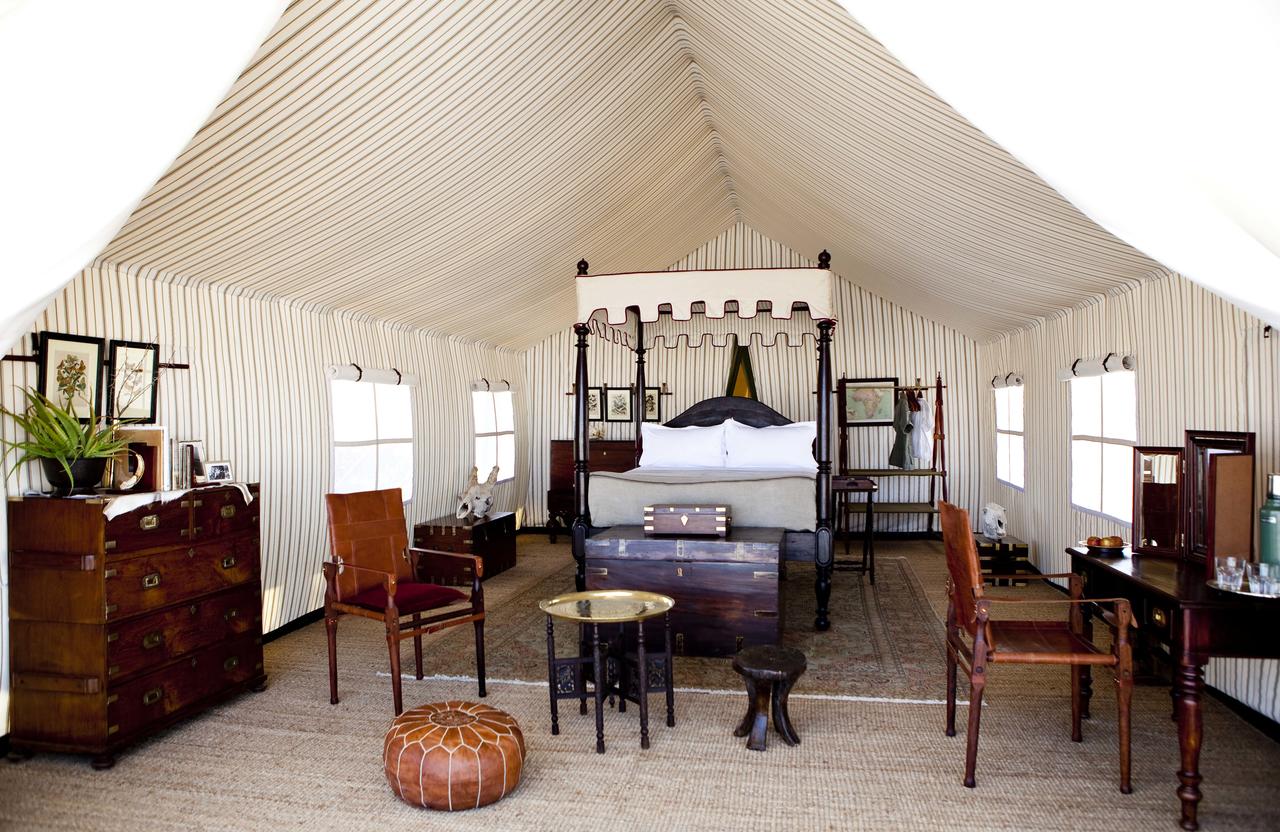 Elegantes Safari-Zelt in Botswana mit Himmelbett, hochwertigen Holzmöbeln und stilvoller Einrichtung im klassischen Kolonialstil.