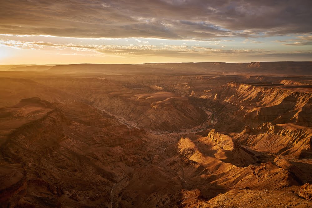 Panoramablick über den Fish River Canyon in Namibia bei Sonnenaufgang mit tief eingeschnittener Schlucht und dramatischen Felsformationen.