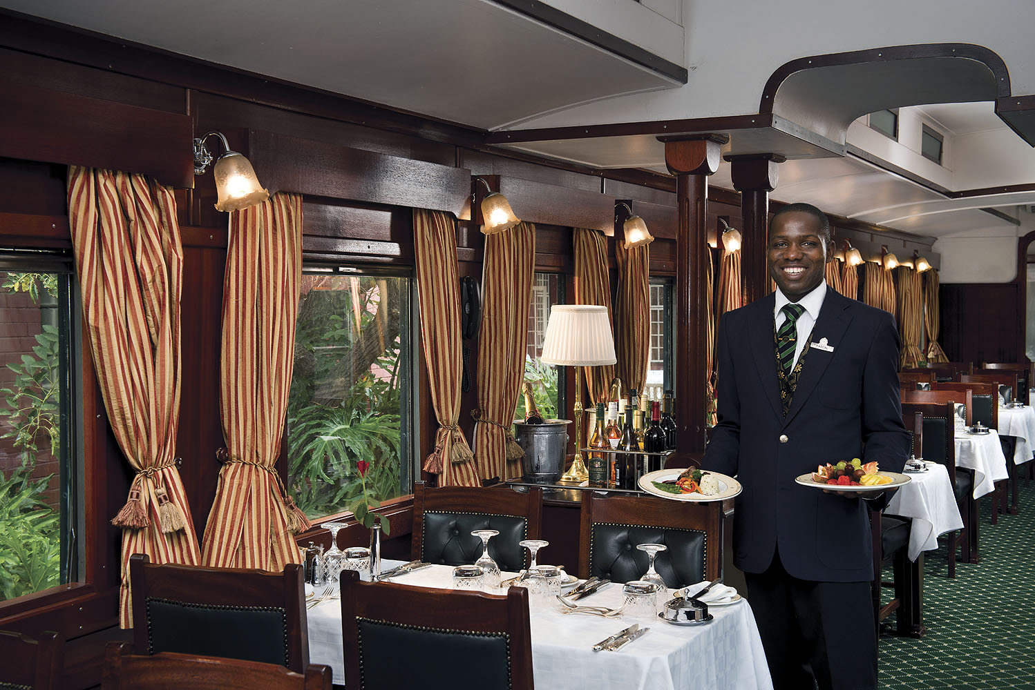 Zugbegleiter serviert Speisen im eleganten Speisewagen des Luxuszuges Rovos Rail in Südafrika.
