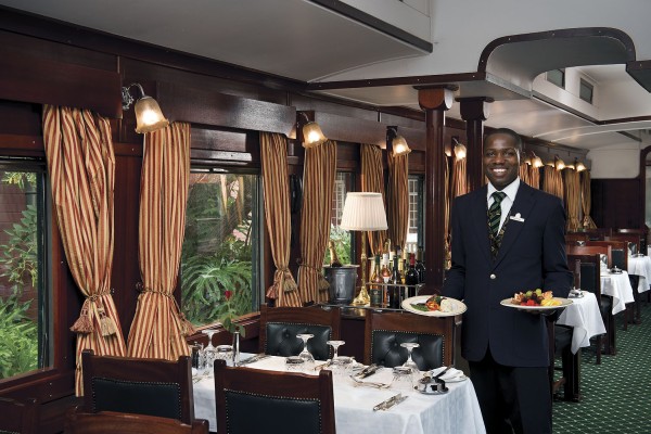 Zugbegleiter serviert Speisen im eleganten Speisewagen des Luxuszuges Rovos Rail in Südafrika.