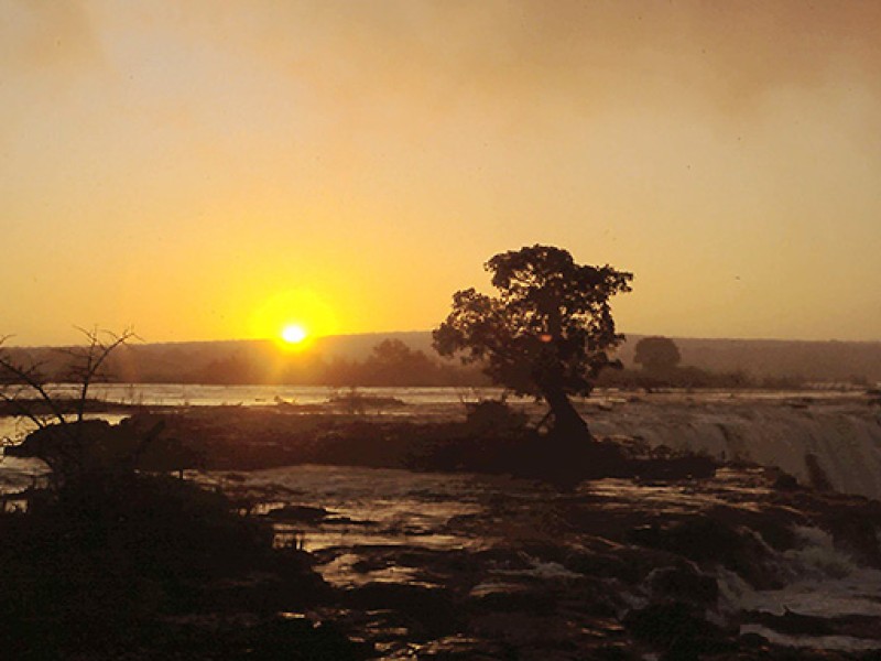 Sonnenaufgang über den Victoriafällen in Sambia nahe dem Devil’s Pool am Sambesi.