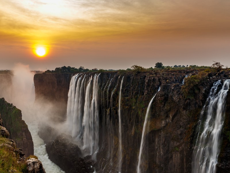 Victoria Falls bei Sonnenuntergang in Zimbabwe, wo der Sambesi spektakulär in die Schlucht stürzt.